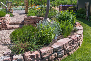 Garden with sandstone wall, paved path and patio and herb bed