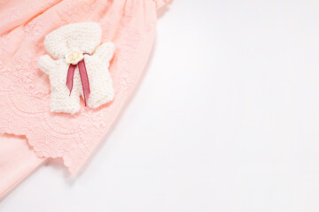 Knitted bear and romper on white background. Copy space. Baby born concept. Flat lay