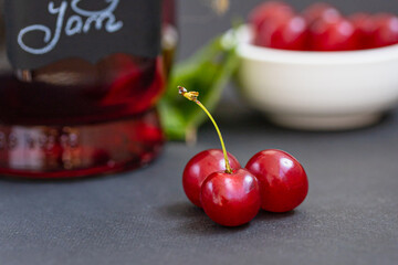 Close up of red ripe cherries on dark background, jam in a glass jar. Cherry Jam Preserves, berry...