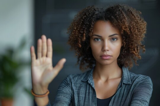 A serious-looking woman with a determined expression making a 'stop' gesture with her hand
