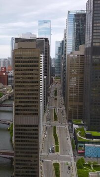 Chicago River with numerous bridges over. Drone rising along the beautiful buildings above the river. Grey day backdrop. Vertical video
