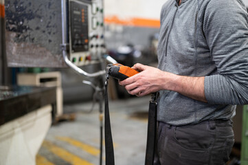 Factory worker. Technician controlling a heavy crane in factory, close up at his hands holding a crane controller. High quality photo