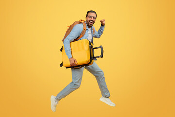 Man jumping with suitcase over yellow background