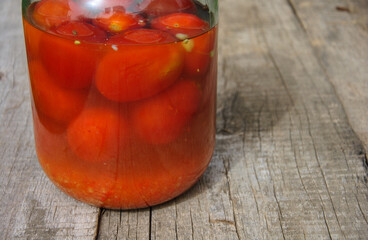 tomato juice in glass. canned tomatoes in a glass jar on a wooden table