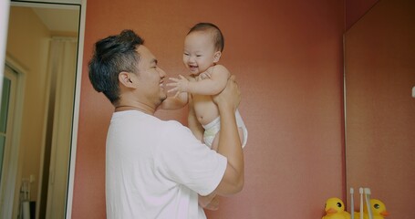 happy asian family father man holding up and play with cute daughter infant baby child girl and...