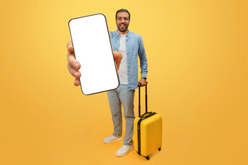 Man holding phone and suitcase on yellow