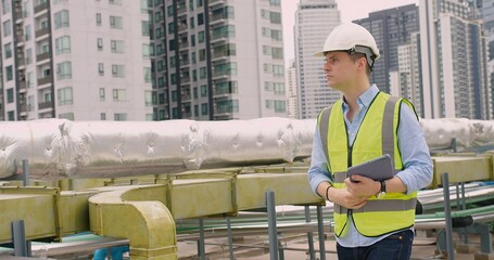 Engineer inspecting insulated pipelines at an industrial site with a digital tablet.