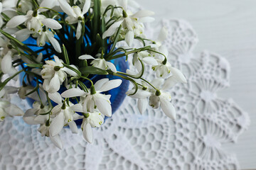 Spring bouquets: a bouquet of snowdrops in a blue vase on an openwork napkin