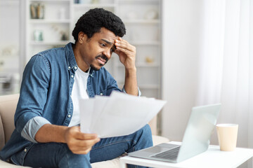 Concerned Black Man Reviewing Documents at Home