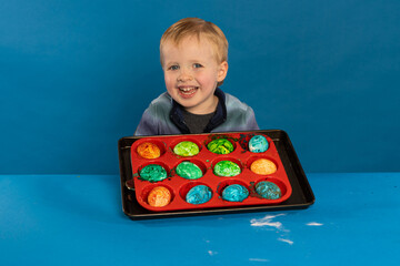 toddler boy makes fizzy dyed easter eggs with baking soda and vinegar for fun stem science preschool activity at home