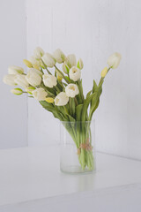 White spring tulips in a vase on a white table. Mock up for displaying works