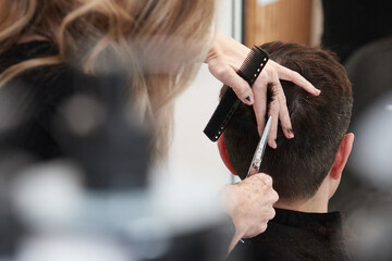 An hairdresser cutting the back part of a woman's hair