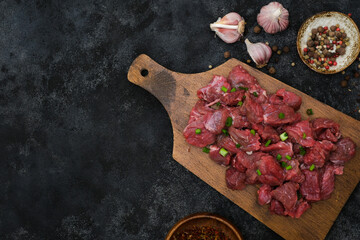 Raw organic meat beef or lamb with garlic, pepper spice on wooden board. Top view with copy space.