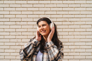 One young girl or woman is listening to music on her wireless headphones and enjoying the sun outdoors	
