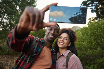Smiling young multiethnic couple taking selfies during a scenic hike