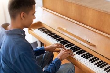 Focused black teen guy practicing piano at home
