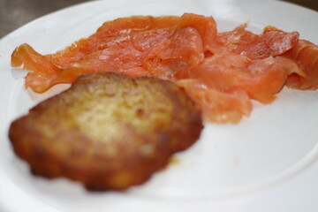 potato pancakes, grated biscuits with salmon, served on a white plate,