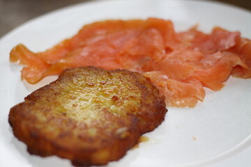 potato pancakes, grated biscuits with salmon, served on a white plate,