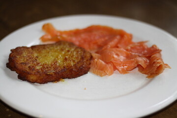 potato pancakes, grated biscuits with salmon, served on a white plate,