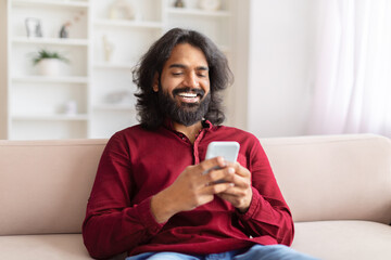 Man smiling at phone in cozy room