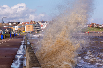 Rough high tide or spring tide with larges waves hitting against the sea wall completely covering...