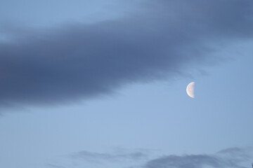 The colorful blue soft sky above the clouds with half moon