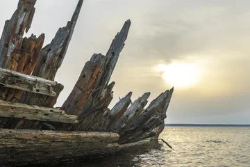 Deurstickers Loksa Estonia - March 31 2024: Shipwreck of the schooner Raketa, built in Rauma, Finland in the post war years for the Soviet Union as compensation for war damages. Skeleton of the ship on sandy beach © Ingrid