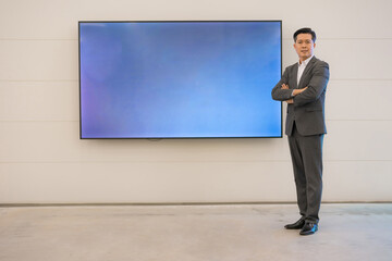 Confident businessman standing by digital display