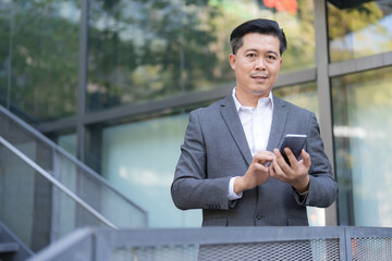 Confident businessman with smartphone outside office building
