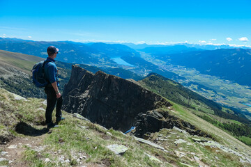 Hiker man on idyllic hiking trail on alpine meadow with scenic view of lake Millstatt seen from...