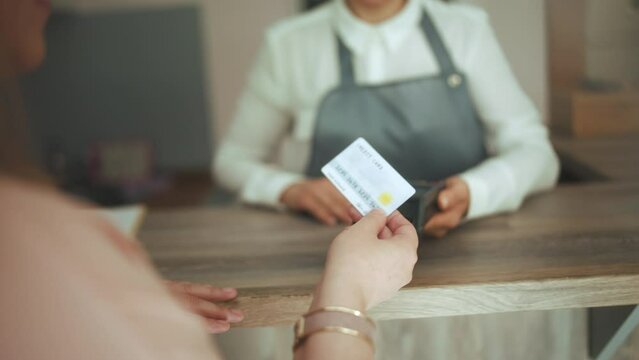 Closeup on woman hair salon worker in modern hair studio with client accepting credit card payments via terminal on reception.