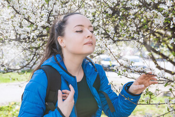 Beautiful woman smell flowering cherry tree in spring garden