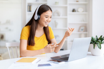 Casual woman with headphones at laptop at home office