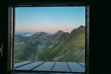 Panoramic sunset view from cottage window of majestic mountain peaks in High Tauern National Park, Salzburg Carinthia border, Austria. Tranquil atmosphere in remote Austrian Alps.Hagener Huette