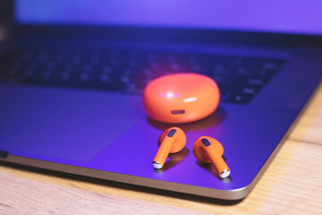 Box and Orange Wireless Bluetooth Earphones lie on the laptop. Modern  Stereo Headphones, Sports...