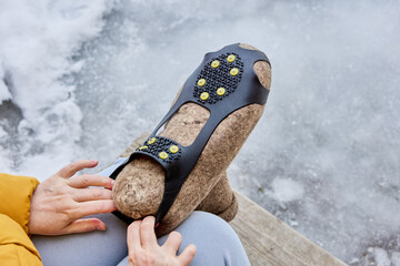 Overshoes with spikes are added to felted boots to prevent slipping on icy pavement and improve...