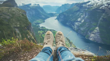 Deurstickers Feet in hiking boots on top of a mountain overlooking the beautiful landscape of a mountain river. © Evgeniia