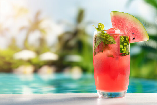 Watermelon lemonade in a glass on a white concrete surface against the background of a luxury tropical hotel