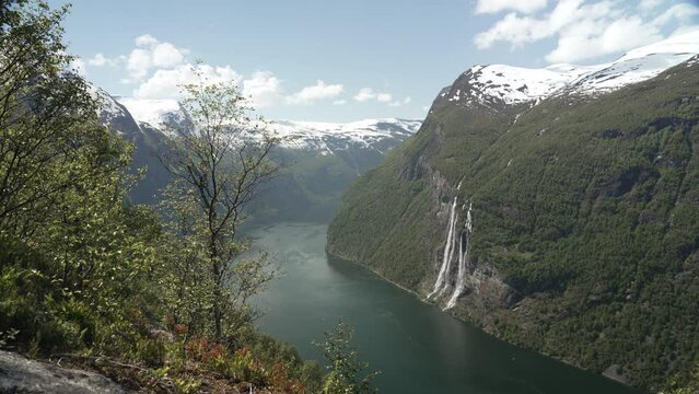 Seven Sisters waterfall in the beautiful Geiranger Fjord, a well known travel destination for cruise ships, offers spectacular views to the norwegian landscape with snow covered mountain ranges.