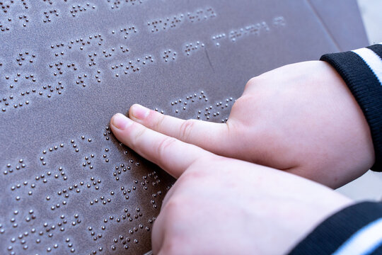 The hand of a blind man reads a Braille text, touching the relief describing the landmark. The concept of accessible environment, inclusive society.