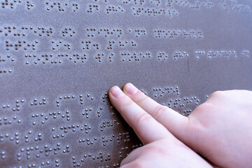 The hand of a blind man reads a Braille text, touching the relief describing the landmark. The...