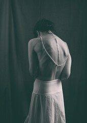 woman seen from behind with a white petticoat-type skirt and a pearl necklace in a romantic attitude VIX