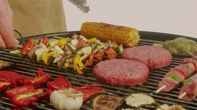 Cooking meat cutlets for humburgers, kebab and vegetables on grill close-up. Making chicken,beef or pork kebab. Barbecue for friends and family. Cafe and restaurant food.