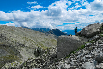 Hiker woman standing on massive rock formation with panoramic view of majestic mountain ridges in High Tauern National Park, Carinthia, Austria. Idyllic hiking trail in Mallnitz, remote Austrian Alps