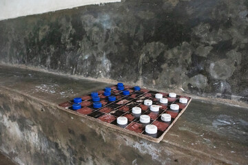 A game of draughts which have blue and white bottle caps for pieces.