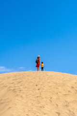 Mother and child smiling in the dunes of Maspalomas in summer, Gran Canaria, Canary Islands