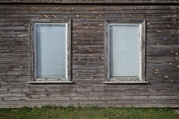 Wooden facade of a building with two windows.