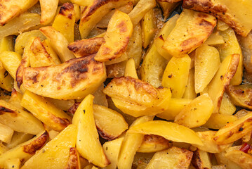 Background of fried potato wedges with spices. Potato. Unhealthy high-calorie foods
