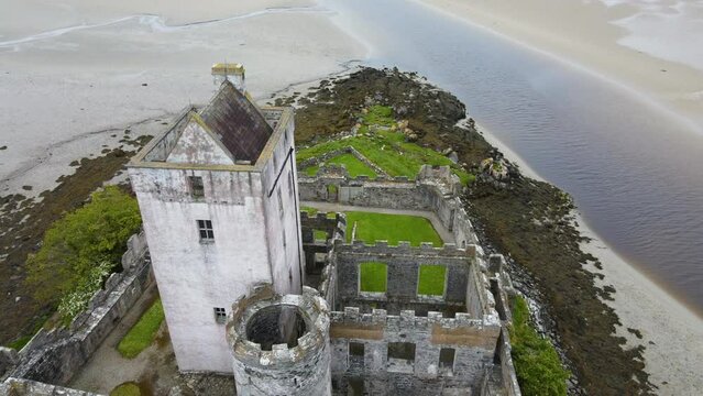 A close drone shot of an old Irish castle along a sandy coastline. Doe Castle, Co. Donegal, Ireland