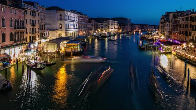 Grand Canal in Venice, Italy day to night transition timelapse. Aerial view on gondolas and city lights from Rialto Bridge. Beautiful and romantic Italian city on water.
